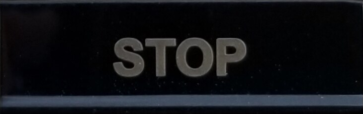 Decoflex balck button with the word stop engraved.